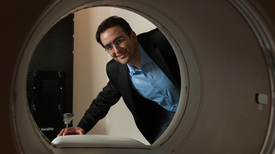 View from inside a CT or MRI-style scanner looking outward as a person leans in to inspect the device.