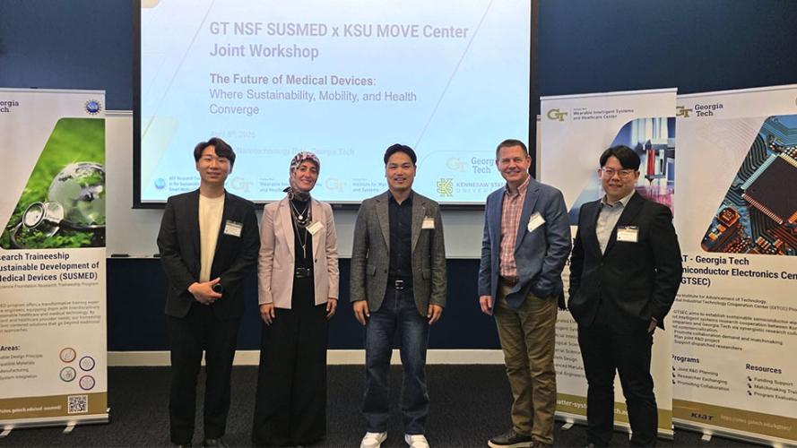 Six workshop organizers stand in front of a projected slide reading “GT NSF SUSMED x KSU MOVE Center Joint Workshop,” with Georgia Tech and Kennesaw State University banners visible on both sides.