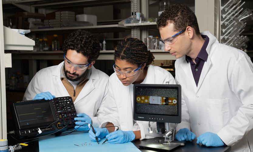 Ramy Ghanim, Joy Jackson, and Alex Abramson test a tiny implantable device in the lab.